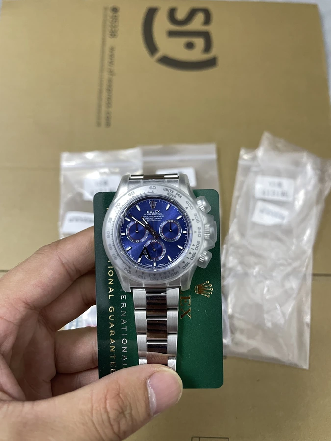 Blue dial watch with three smaller subdials, a numbered bezel and silver bracelet, photographed in hand.
