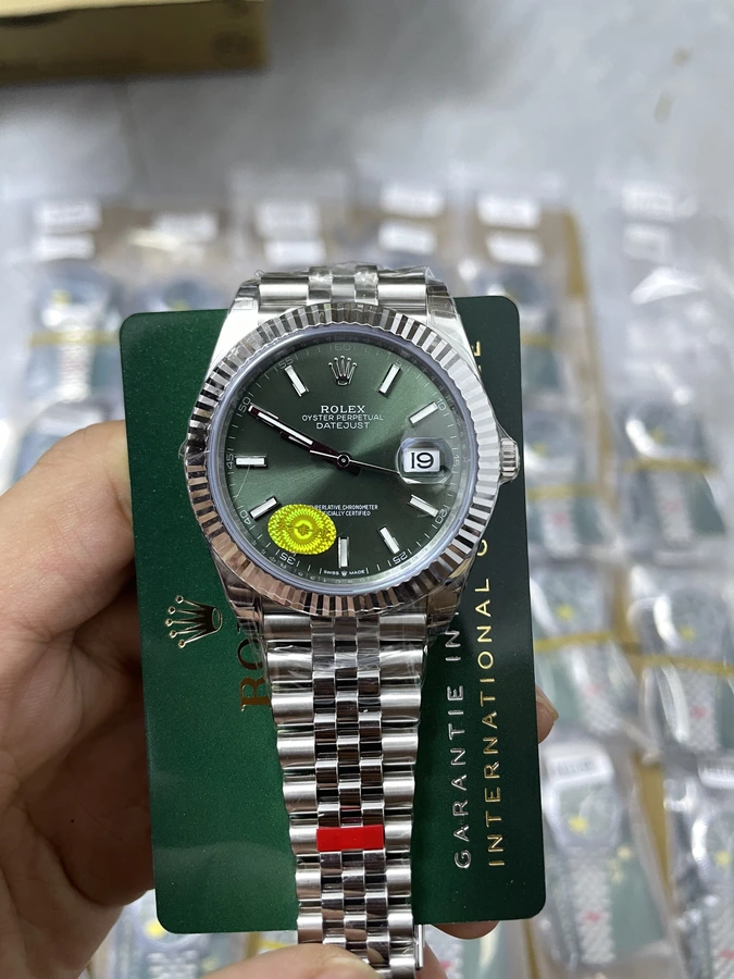 Green dial watch with a silver bracelet and fluted-style bezel, photographed in hand.