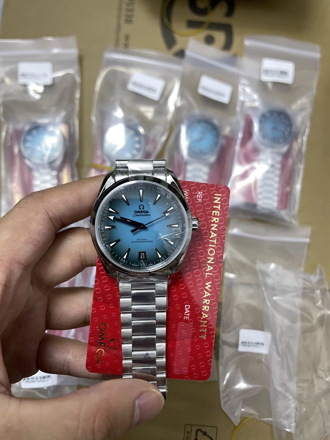 Light blue dial watch with a silver bracelet and red presentation card, photographed in hand.