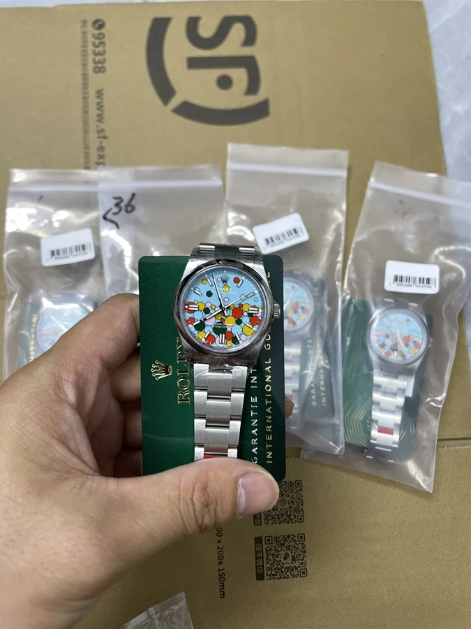 Colorful patterned dial watch with a silver bracelet, photographed in hand on a green presentation card.